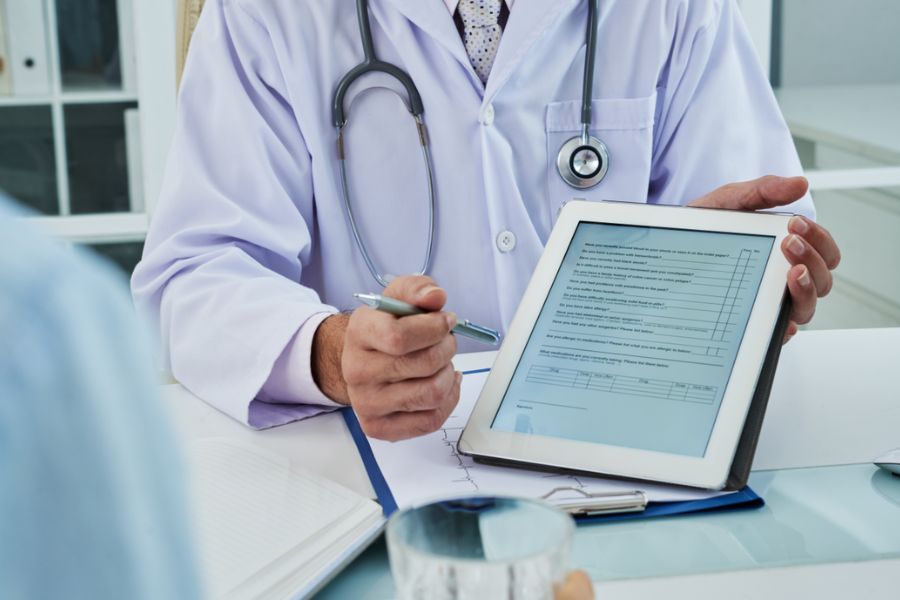 Médico mostrando questionário em tablet durante consulta
